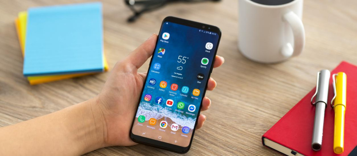 İstanbul, Turkey - February 2, 2019: Hand holding a smart phone on a wooden desk. The smart phone is an Samsung Galaxy S9 plus. Samsung Galaxy is a touchscreen smart phone produced by Samsung Electronics.