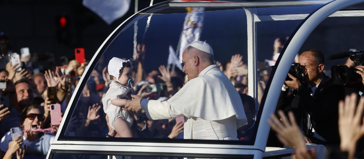 El papa León XIV hace alguna parada para acercarse a varios bebés en su recorrido por Madrid en el papamóvil para dirigirse a la Plaza de Lima