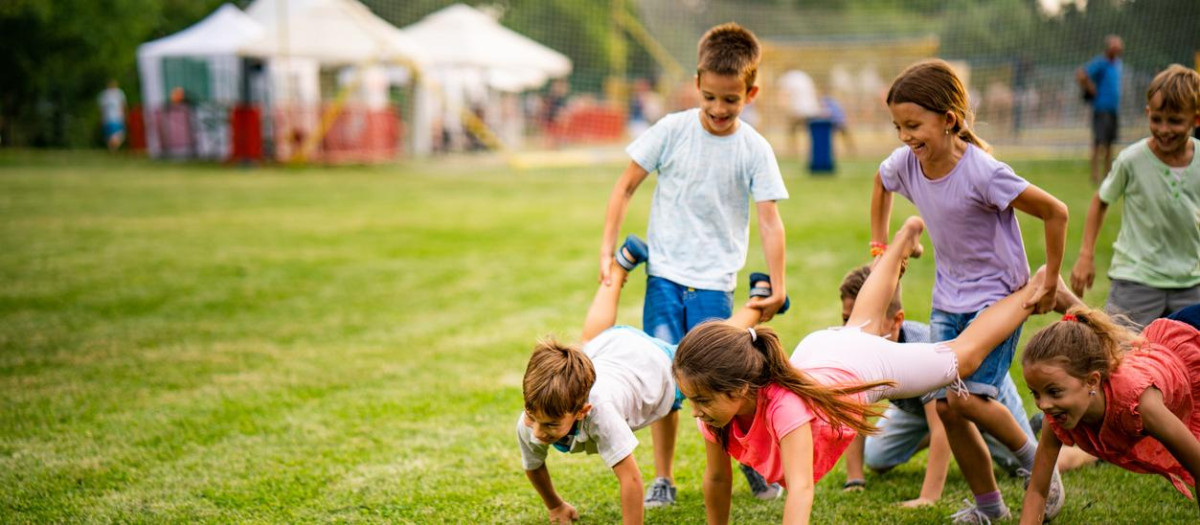 Below view of playful children having fun in wheelbarrow race.