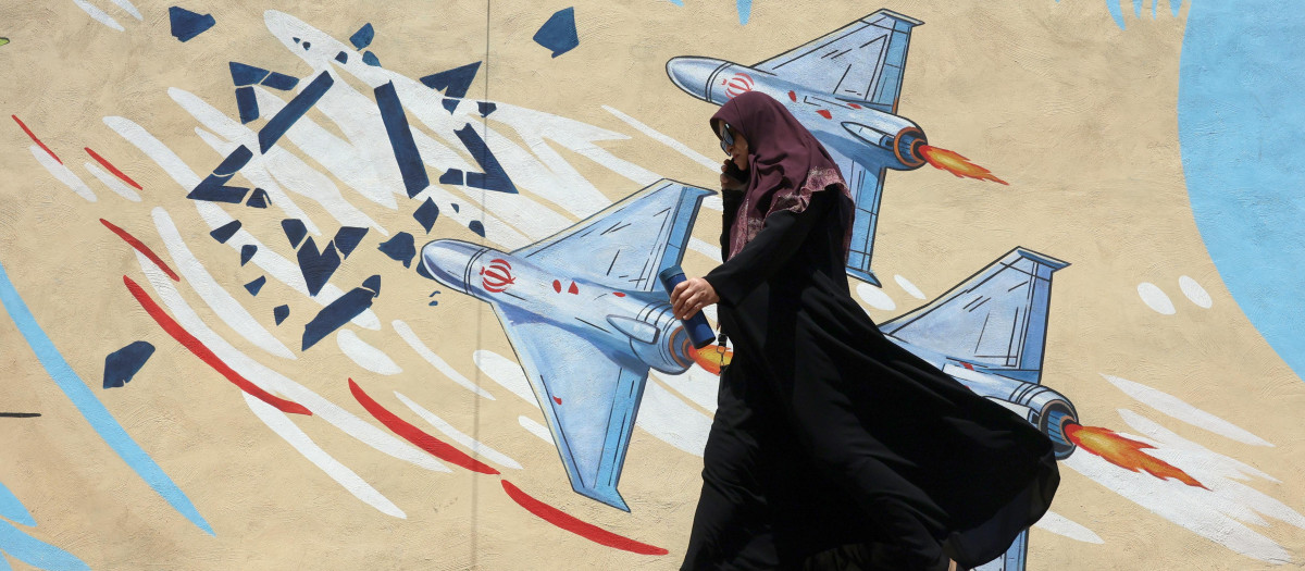 Una mujer iraní pasea junto a un mural anti-israelí
