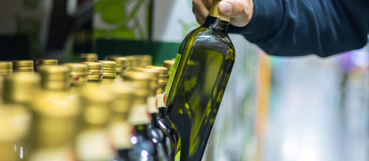 un hombre coge una botella de aceite de oliva en un supermercado