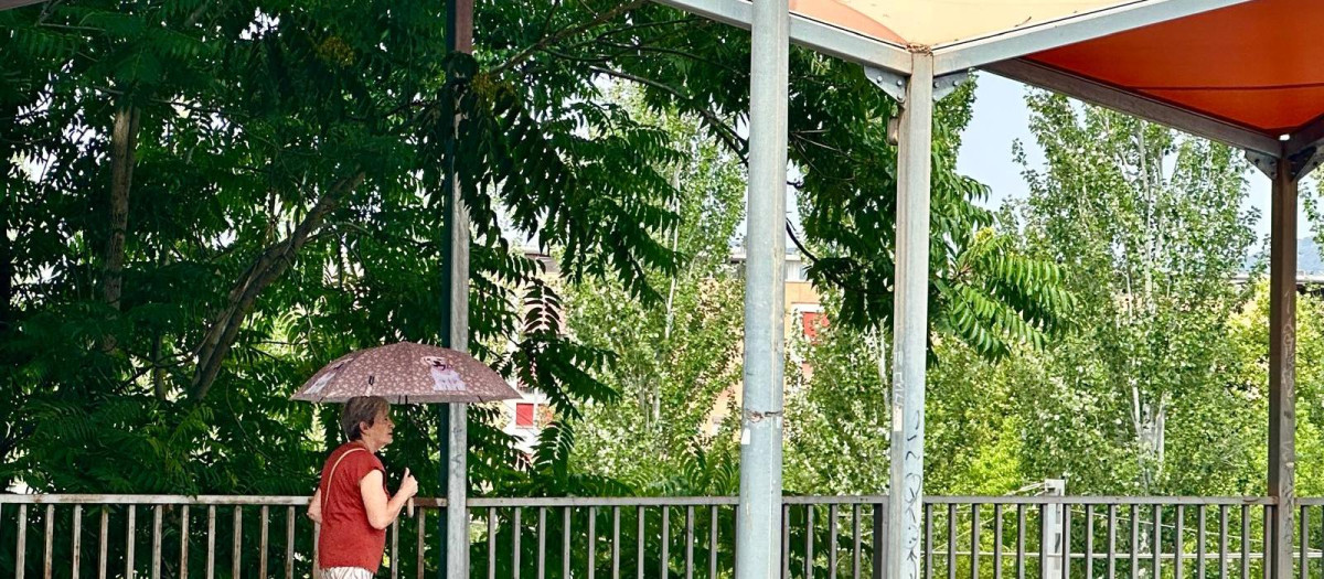 Una señora pasa por el viaducto de Arroyo del Moro, en plena ola de calor