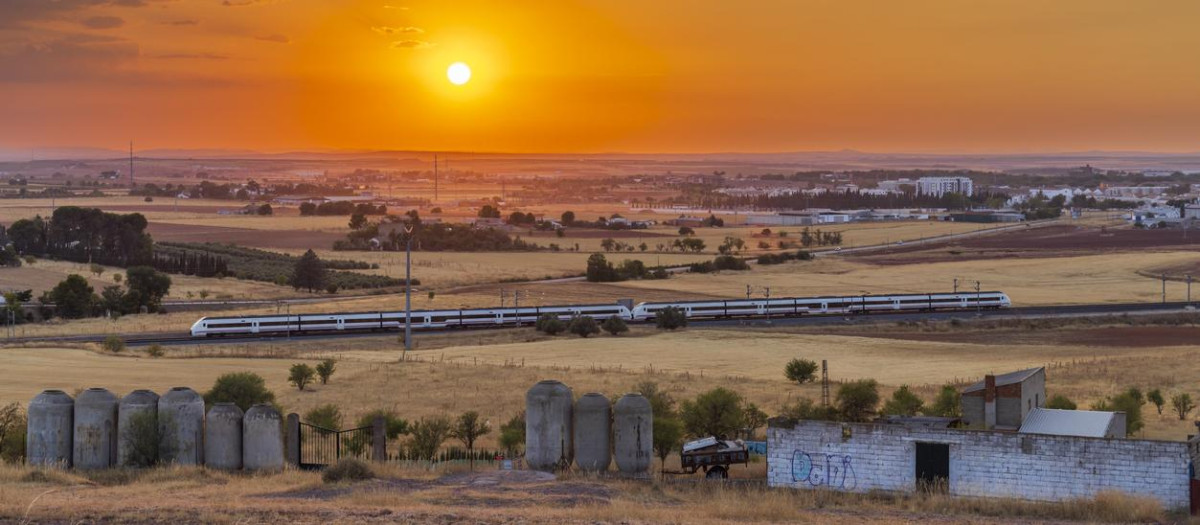 Scenic view of a high speed train traveling through the vast Castile La Mancha region during a vibrant sunset, near Alcazar de San Juan, Spain