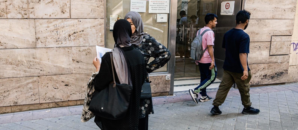 Varios migrantes esperan en el exterior de una oficina de la Seguridad Social
