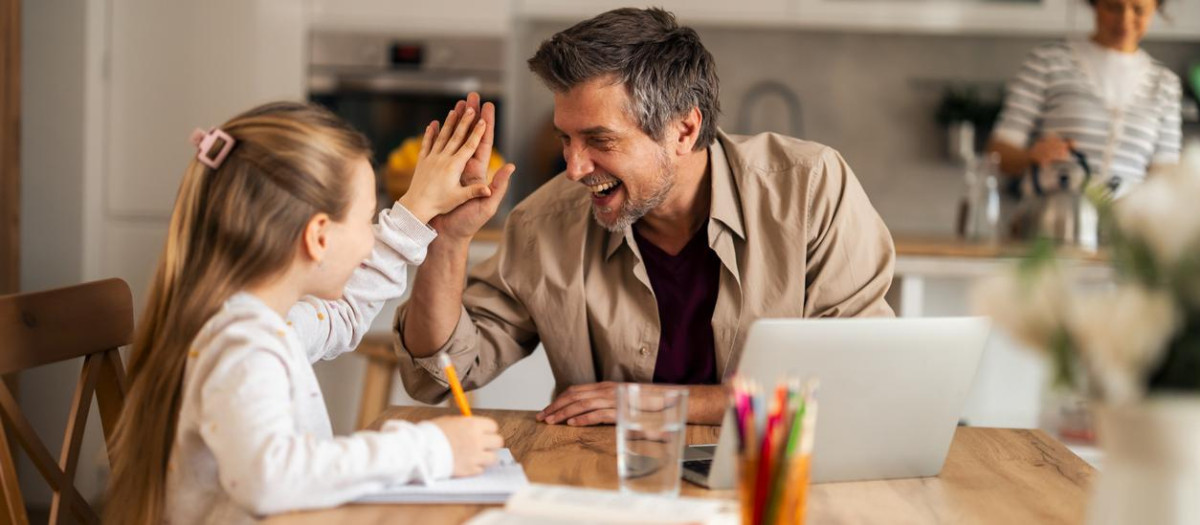 A cheerful dad helps his daughter with her homework in a cozy kitchen setting, showcasing family support and bonding. The warm atmosphere highlights educational and familial commitment.