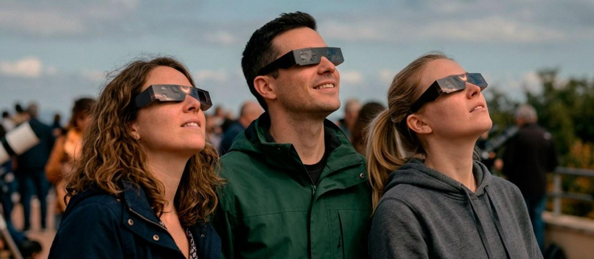 Imagen de tres personas con las gafas solares para contemplar el eclipse total.