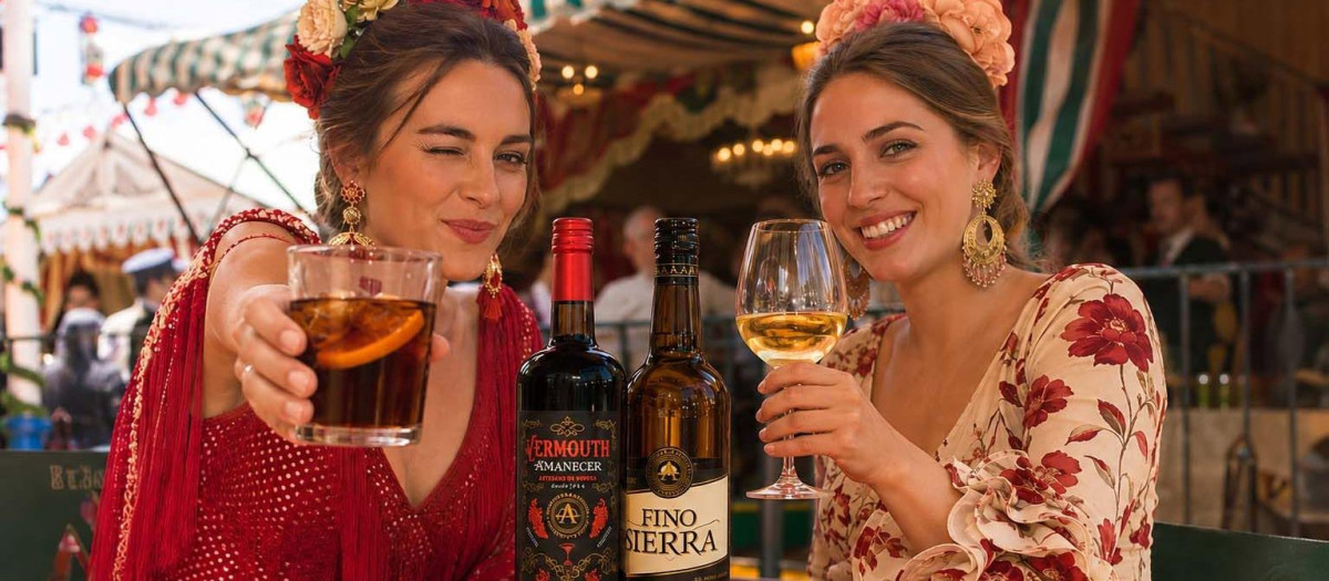 Dos mujeres brindan con productos de La Aurora en una feria