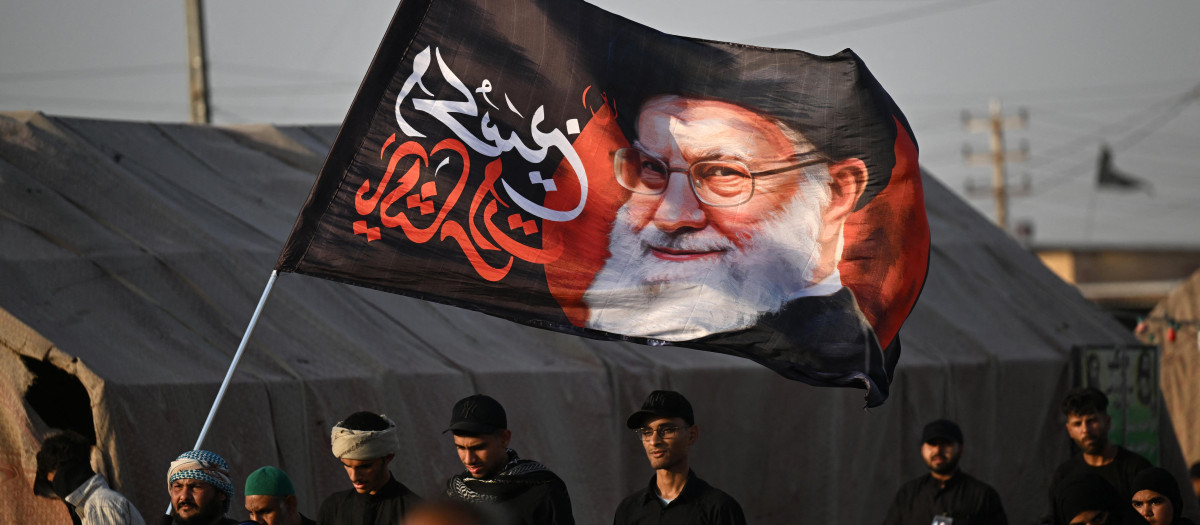 Peregrinos musulmanes chiítas portan una bandera con el retrato del asesinado líder supremo de Irán, el ayatolá Ali Khamenei, mientras marchan hacia la ciudad santa de Karbala,