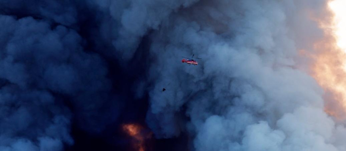 A firefighting helicopter attempts to extinguish a fire at the Russian e-commerce firm Wildberries' logistics complexes in the town of Elektrostal outside Moscow on July 18, 2026. A Ukrainian drone attack on two logistics centres in Russia killed eight people and injured 24, officials said on July 18, 2026, when the Moscow region reported a new wave of drone strikes. Russian e-commerce firm Wildberries said its logistics complexes in Kotovsk and Elektrostal, in the Tambov and Moscow regions respectively, came under attack. One person was killed and 37 were injured at the Elektrostal warehouse, according to the region's governor, Andrei Vorobyov. (Photo by TATYANA MAKEYEVA / AFP)