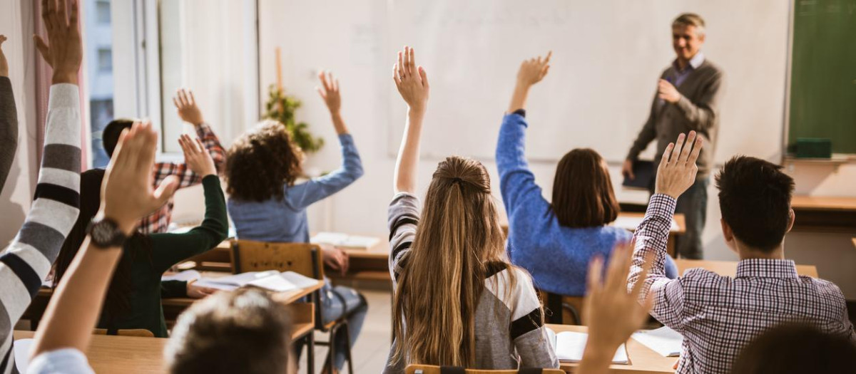 Estudiantes levantando las manos de una clase
