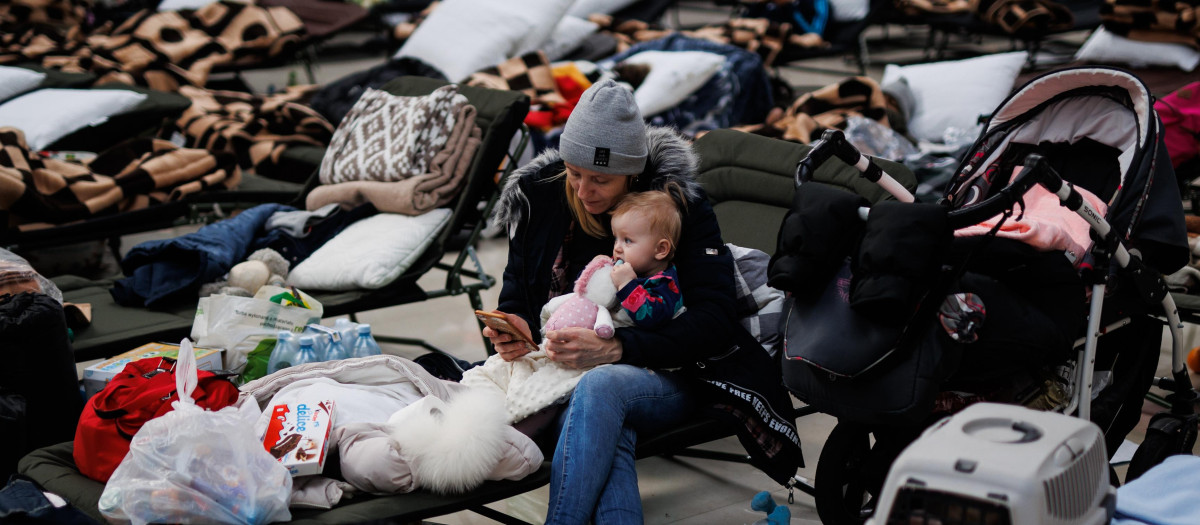 Una mujer con un bebé, en un centro comercial habilitado para los refugiados, en Mylny, a 27 de febrero de 2022, en Polonia