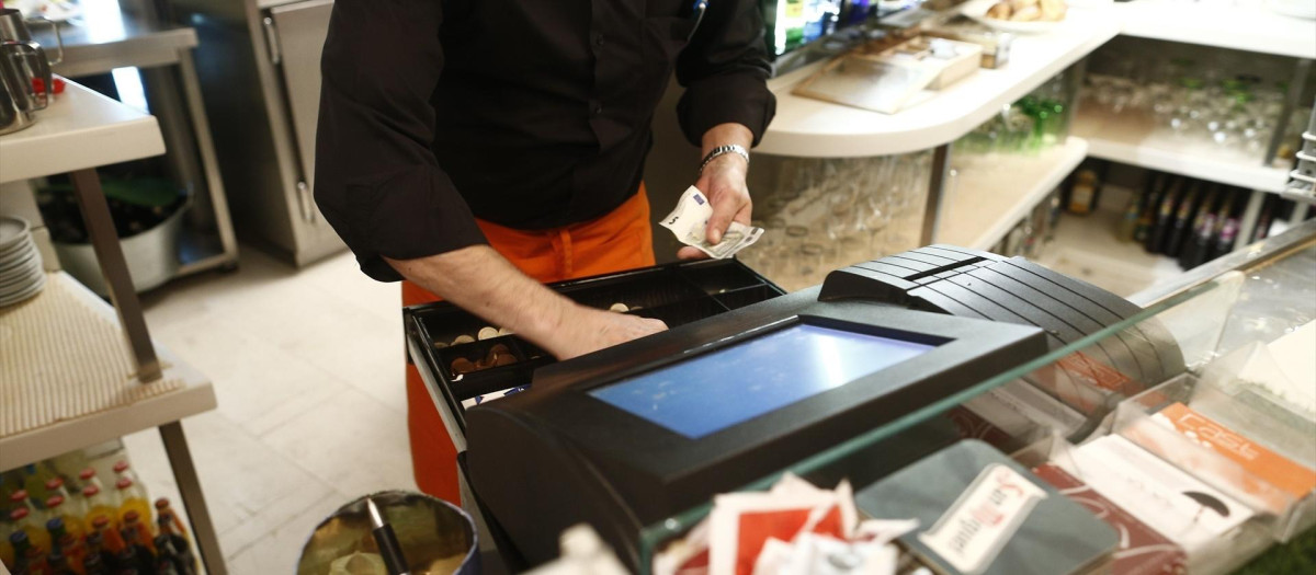 Un camarero con la caja registradora.