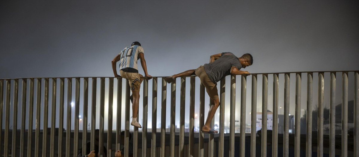 Varias personas saltan la valla que hace de frontera entre Ceuta y Marruecos.