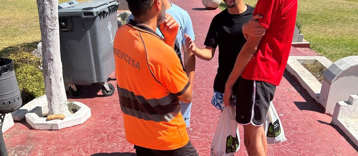 Un operario del cementerio atiende alguna pregunta de tres inmigrantes en Ceuta