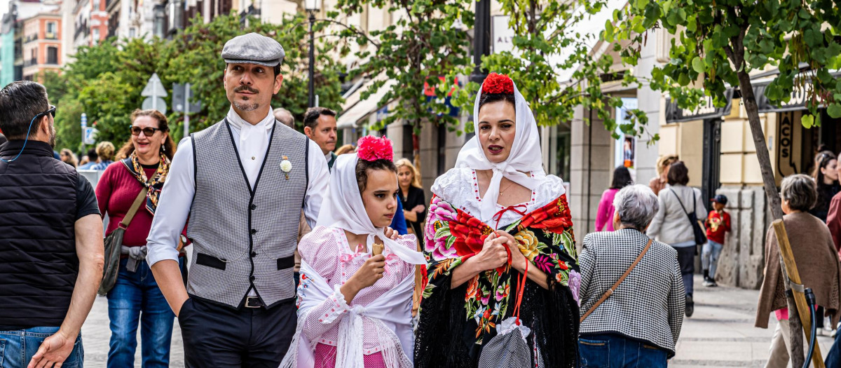 Una familia caminando por la calle, vestida con los trajes de chulapos típicos de Madrid