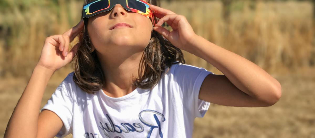 Una niña mirando el eclipse con gafas