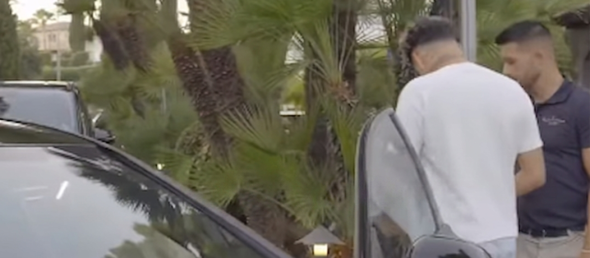 El aparcacoches de negro junto al dueño del coche de blanco