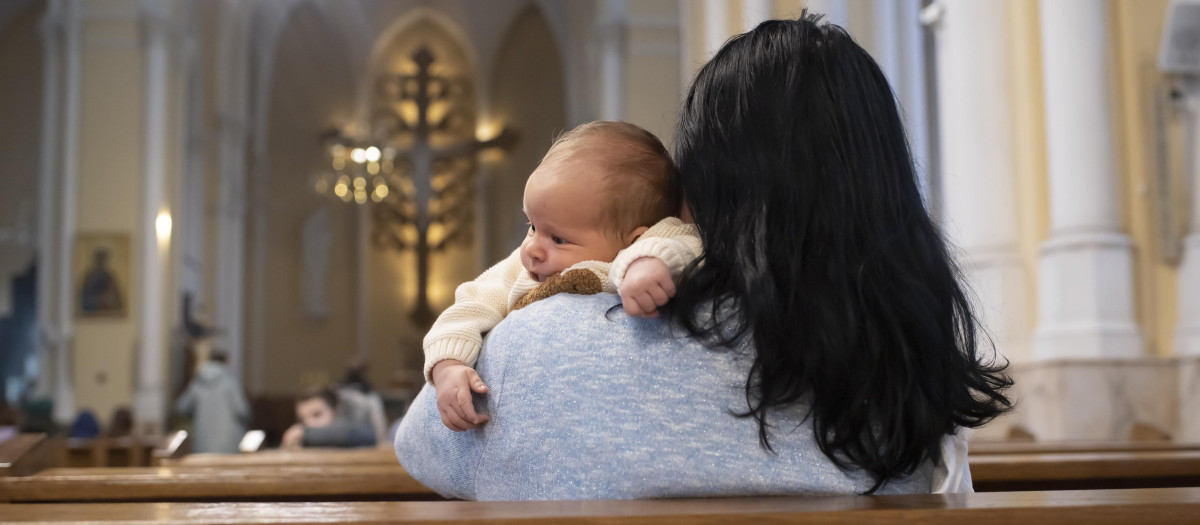 Una madre junto a su bebé, esperando que empiece la Eucaristía