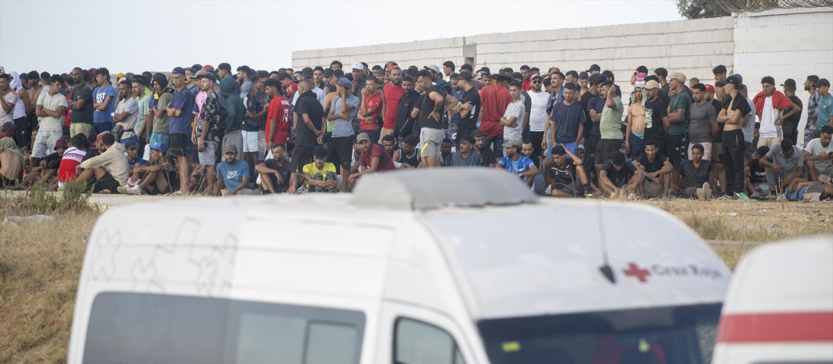 Miembros de la Cruz Roja atienden a varios inmigrantes en la playa del Trampolín