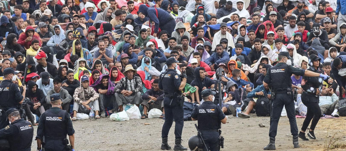 FOTODELDIA CEUTA, 21/08/2026.- La policía vigila a inmigrantes que continúan viviendo en las inmediaciones de la playa del Trampolín en Ceuta, este viernes. El secretario de Estado Juventud e Infancia, Rubén Pérez Correa, ha considerado "factible" llevar a cabo "en un plazo de pocas semanas" el traslado de 500 niñas migrantes no acompañadas desde Ceuta a la Península y, para ello, confía en la "voluntad" del Gobierno de la ciudad autónoma. EFE/Reduan