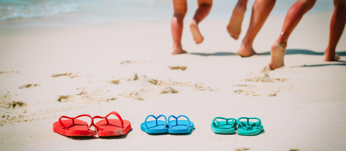 Imagen de archivo de unos niños corriendo por una playa, junto a unas chanclas