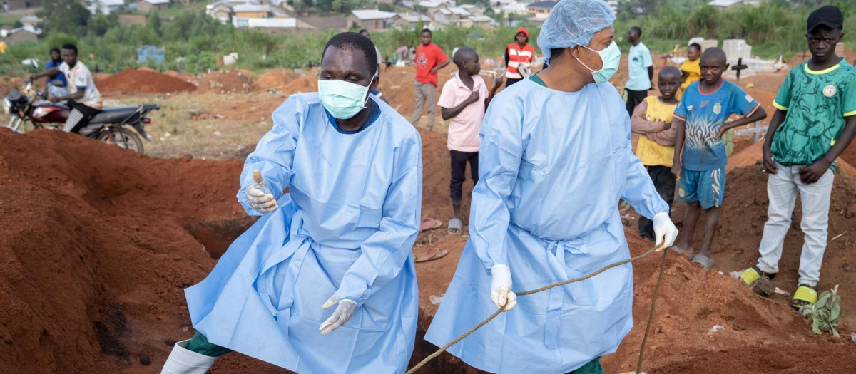 Personas con ropa de protección se preparan para el entierro de fallecidos por la epidemia