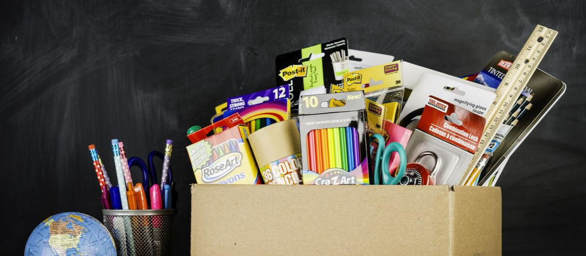 "Suffolk, Virginia, USA - August 22, 2013: A horizontal studio shot of a a donation box for school supplies shot against an authentic school chalkboard. Next to the box is a miniature school bus, world globe and a collection of new pens and pencils."
