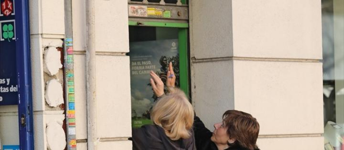 Una autónoma sube la persiana de su negocio.