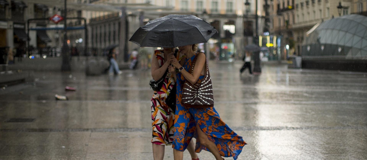 Dos mujeres se protegen de la lluvia en la Puerta del Sol de Madrid