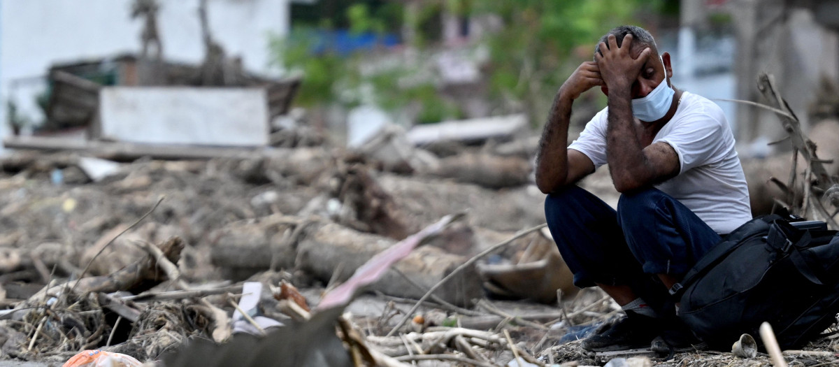 Un hombre se sienta junto a los escombros mientras recupera sus pertenencias tras unas inundaciones repentinas en Devighat, en el distrito nepalí de Nuwakot