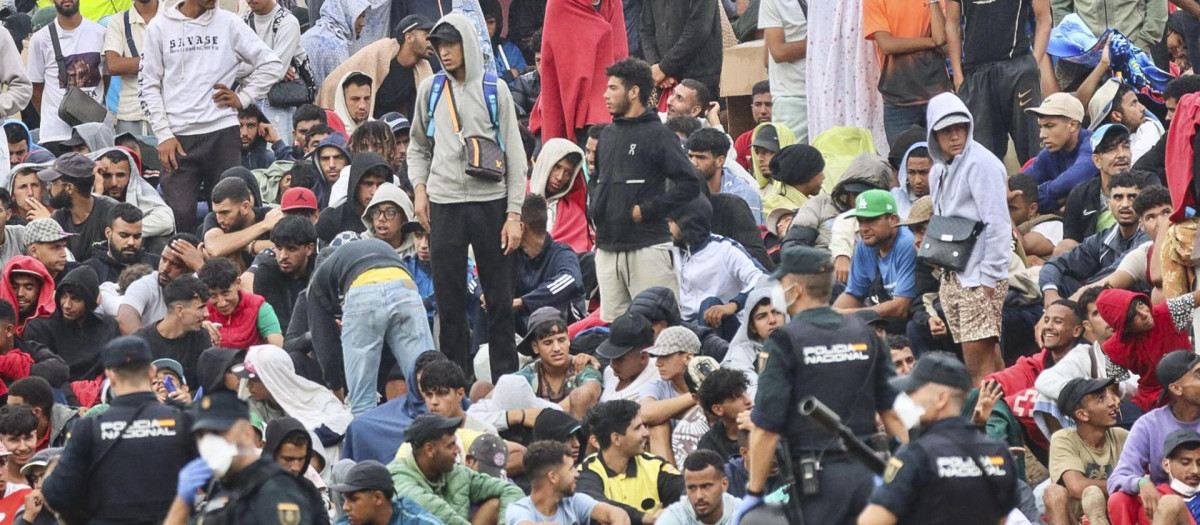 Un grupo de policías custodiando a un grupo de inmigrantes ilegales en Ceuta