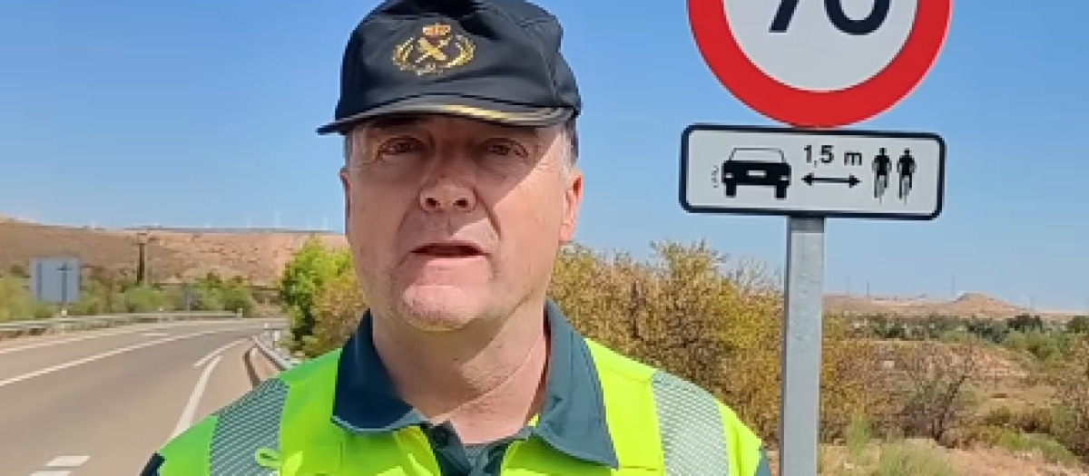 El agente explica la distancia lateral junto a una señal de carretera