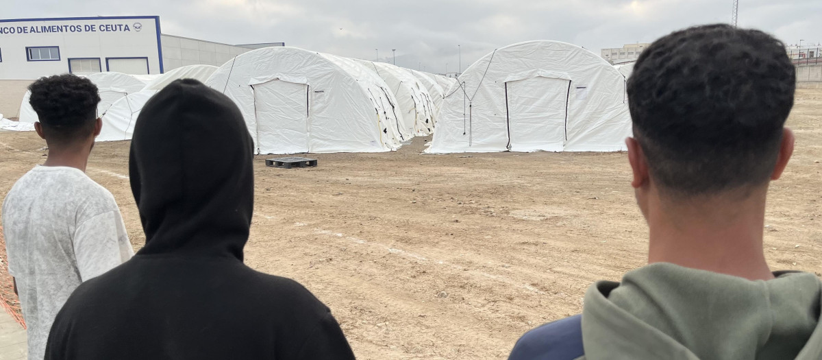 Tres inmigrantes junto al nuevo campamento, en el puerto de Ceuta