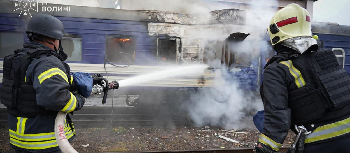 Bomberos rociando agua sobre un vagón de tren dañado por un ataque con drones cerca de la frontera con Polonia. Polonia y Ucrania