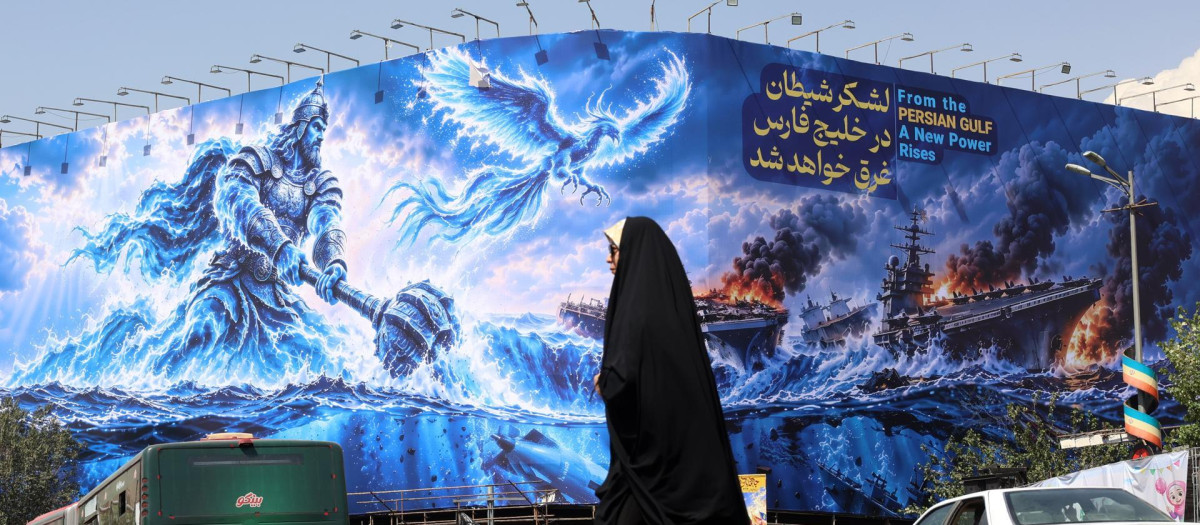 Una mujer iraní camina junto a una valla propagandista antiestadounidense en la plaza Enghelab de Teherán