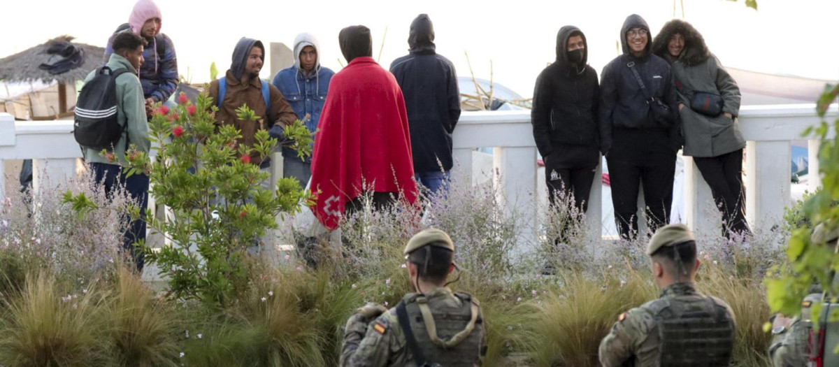 Miembros del ejército observan a unos inmigrantes que viven en las chozas de la playa Benítez