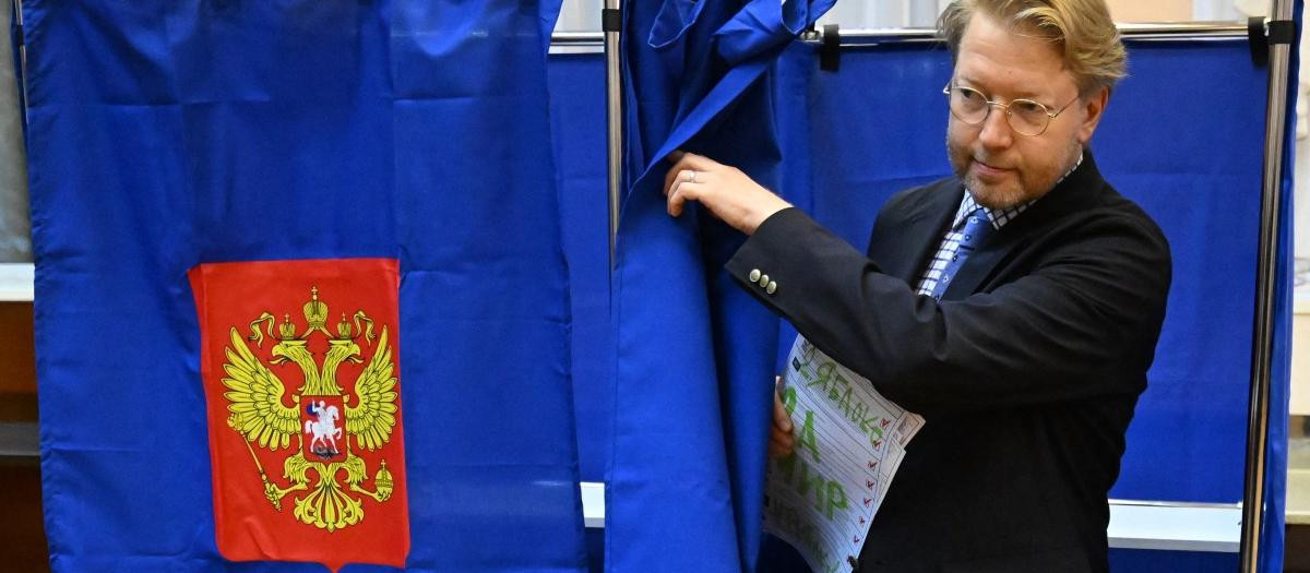 Russia's liberal Yabloko party leader Nikolay Rybakov leaves a voting booth with his ballot with a marker writing "For peace" during Russia's parliamentary election at a polling station in Saint Petersburg on September 20, 2026. (Photo by Olga MALTSEVA / AFP)