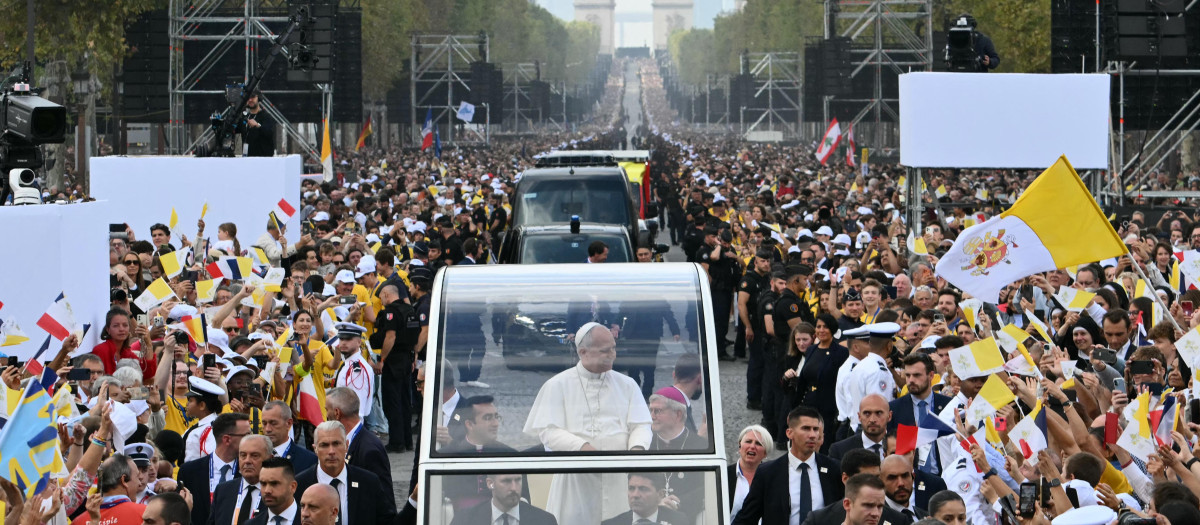 León XIV saluda a la multitud desde el «Papamóvil» mientras recorre la avenida de los Campos Elíseos, con el Arco del Triunfo al fondo, de camino a la plaza de la Concordia, en el centro de París