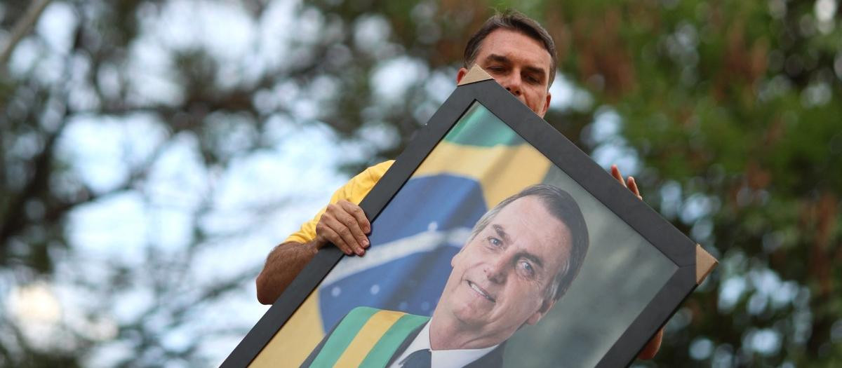 Brazilian right-wing presidential candidate Flavio Bolsonaro holds a picture of his father, convicted former President Jair Bolsonaro, during a motorcade with supporters in Goiania, Brazil, on September 27, 2026. Brazil will hold presidential election on October 4, 2026. (Photo by Sergio Lima / AFP)