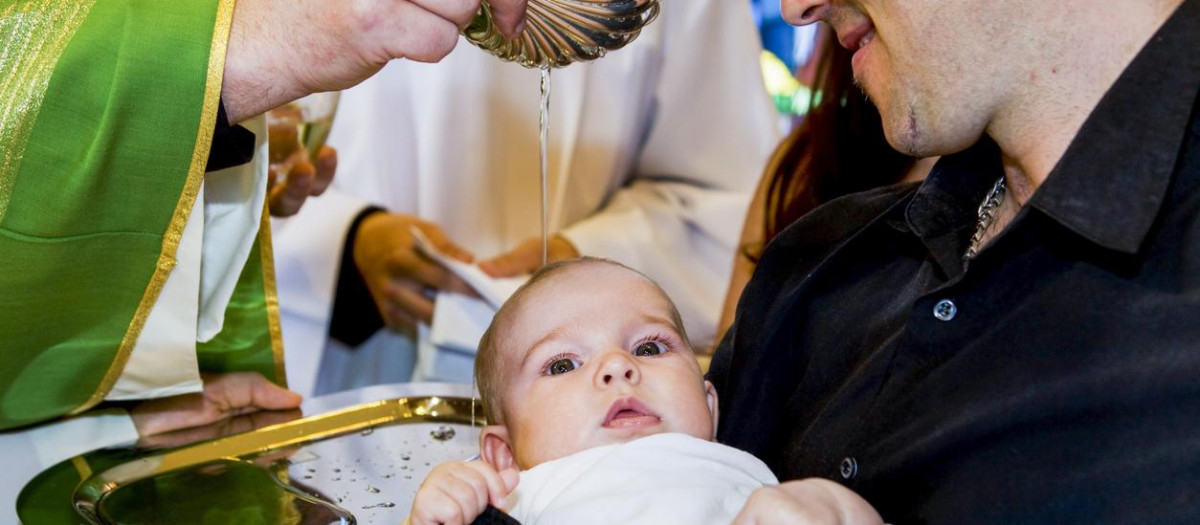 Priest is baptizing little baby. in a church,father holding baby