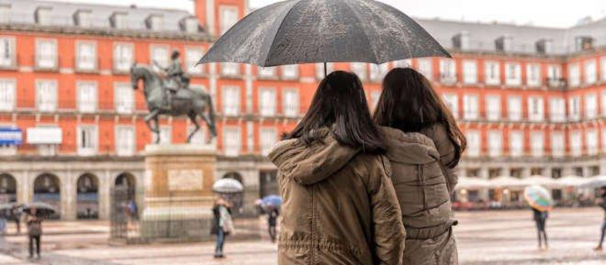 Dos mujeres se protegen de la lluvia en la Plaza Mayor