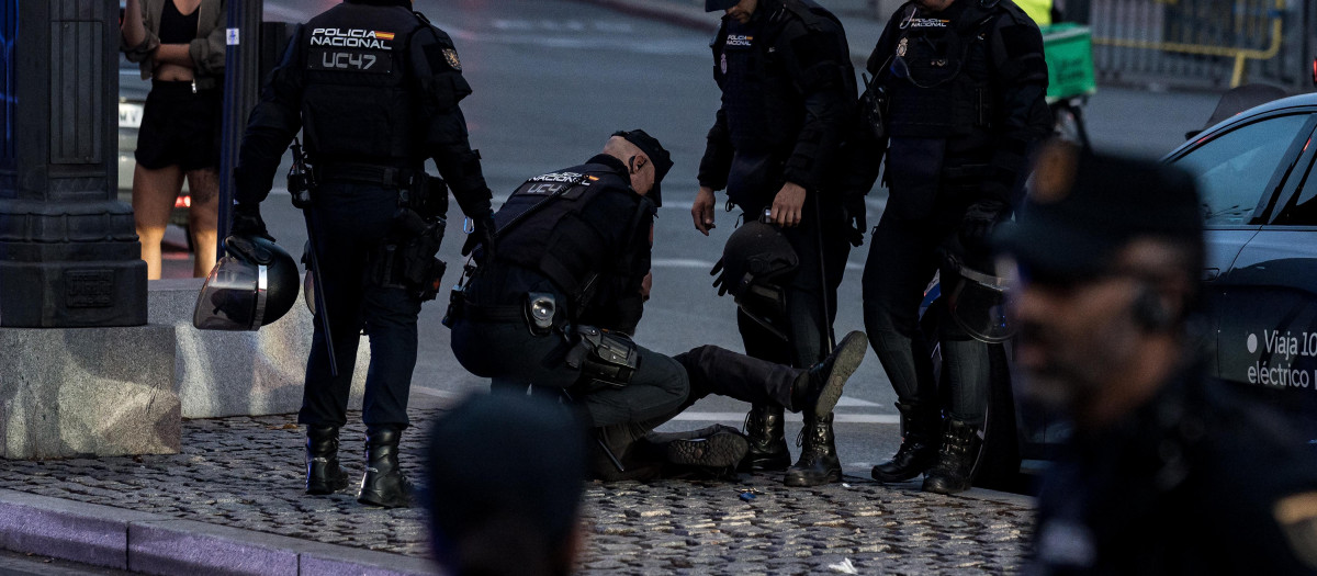 Varios agentes de la Policía Nacional detienen a un persona durante una concentración de protesta contra la acampada en la Puerta del Sol