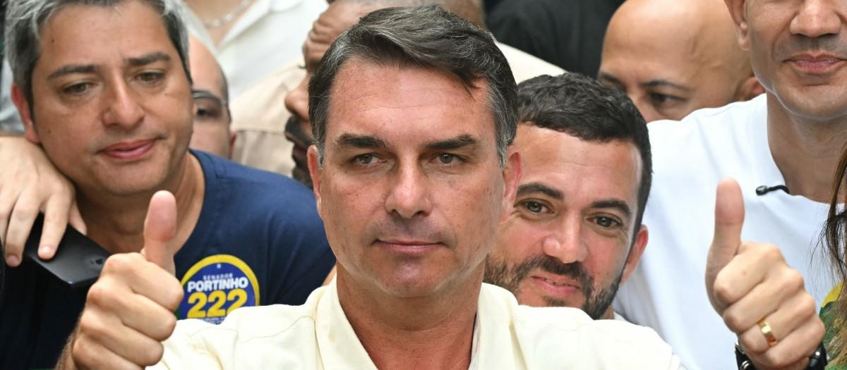 Brazil's right-wing senator and presidential candidate for the Liberal Party (PL) Flavio Bolsonaro gives thumbs up in front of Rio de Janeiro gubernatorial candidate Douglas Ruas (C, back), as he leaves a polling station after voting during the presidential election in Rio de Janeiro, Brazil, on October 4, 2026. Brazilians head to the polls deeply polarized in a nail-biting first-round presidential election and under the shadow of US President Donald Trump, who has backed conservative candidates in recent elections in Latin America. (Photo by MAURO PIMENTEL / AFP)