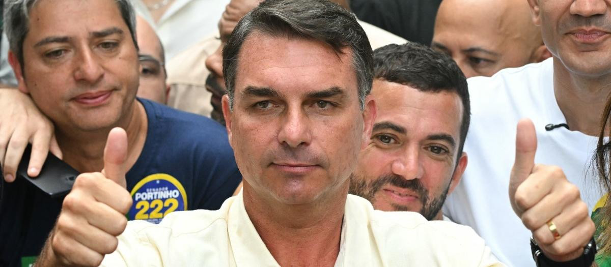 Brazil's right-wing senator and presidential candidate for the Liberal Party (PL) Flavio Bolsonaro gives thumbs up in front of Rio de Janeiro gubernatorial candidate Douglas Ruas (C, back), as he leaves a polling station after voting during the presidential election in Rio de Janeiro, Brazil, on October 4, 2026. Brazilians head to the polls deeply polarized in a nail-biting first-round presidential election and under the shadow of US President Donald Trump, who has backed conservative candidates in recent elections in Latin America. (Photo by MAURO PIMENTEL / AFP)