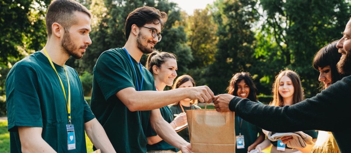 A couple is taking a bag of food at the food and clothes bank. Volunteers are working together at the humanitarian aid project.