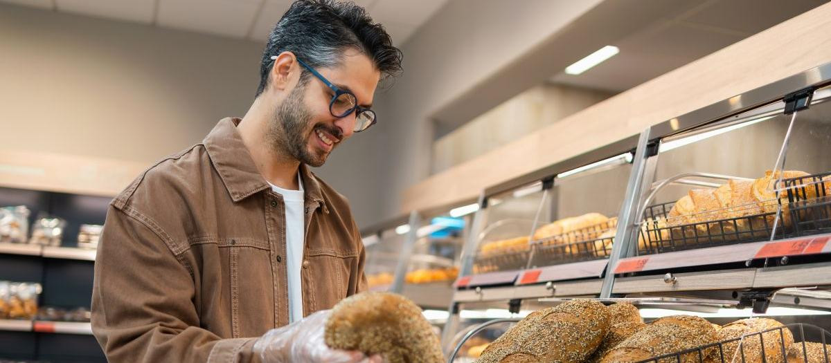 Imagen de archivo de un hombre comprando un pan en un supermercado