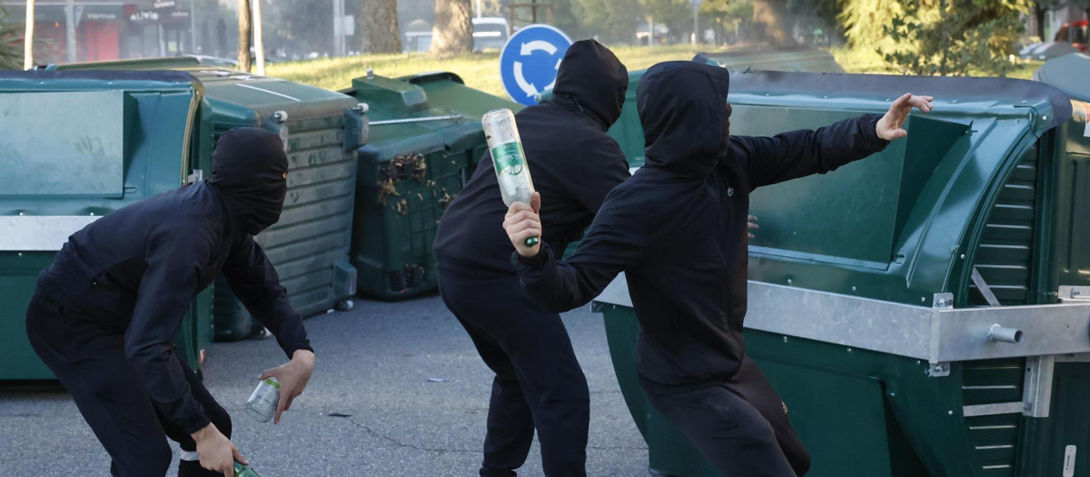 Jóvenes radicales se parapetan tras unos contenedores y lanzan botellas de vidrio contra la Policía