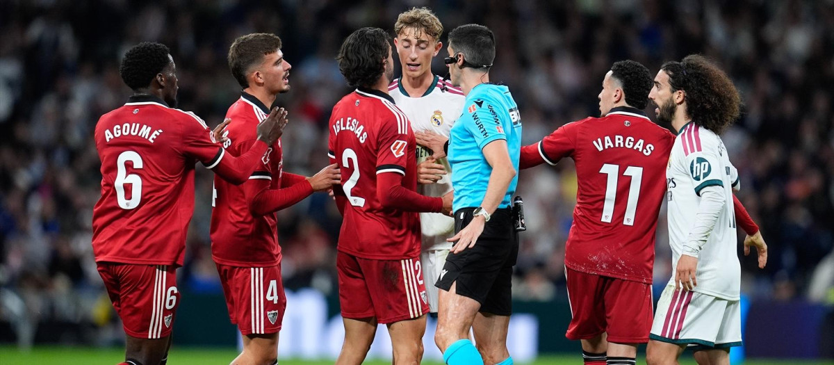 Busquets Ferrer habla con los jugadores de Real Madrid y Sevilla con Peque Fernández en el suelo