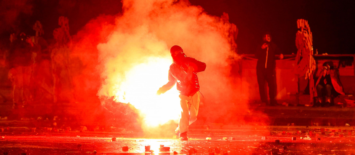 Un manifestante en Albania lanza una un objeto incendiario contra los agentes antidisturbios