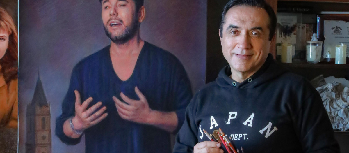 El artista malagueño, pinceles en mano, posa junto a uno de sus retratos
